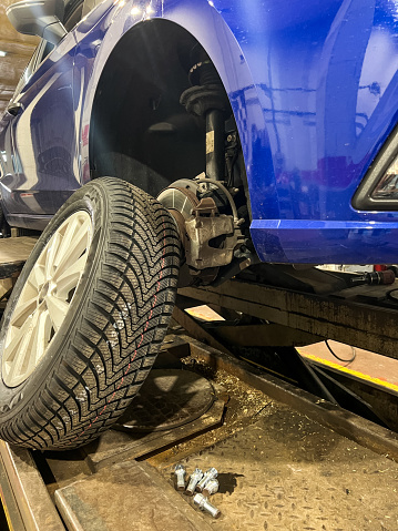 Close up of a wheel of a car uploaded on a lift in a car workshop for changing and repairing wheels