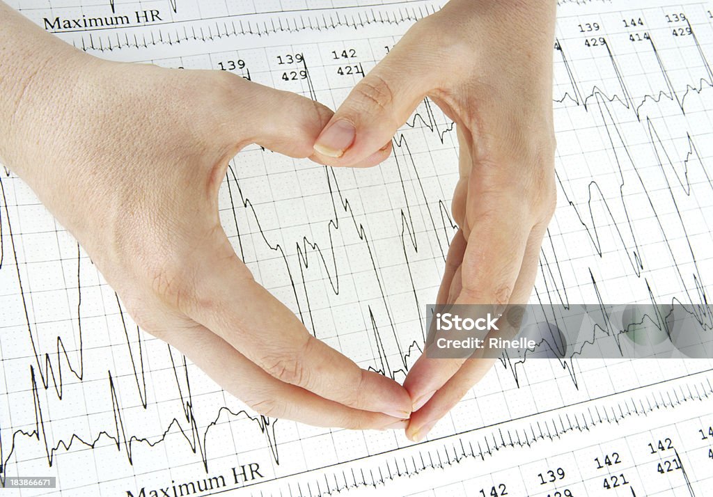 Heartbeat A woman's hands making a heart shape over the top of a heart monitor printout. Beauty Stock Photo