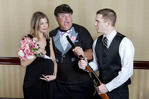Shotgun wedding comedy bride and groom pose. comedy about a pregnant bride and a low class groom in a tee shirt tuxedo being brought to the alter at gunpointClick Here to view my other Cityscapes and Architecture: baby gun stock pictures, royalty-free photos & images