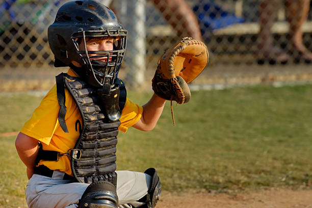 Young boy playing catcher in Youth League baseball game Action portrait of seven year old in catcher uniform crouched and ready to receive ball from pitcher elbow pad stock pictures, royalty-free photos & images