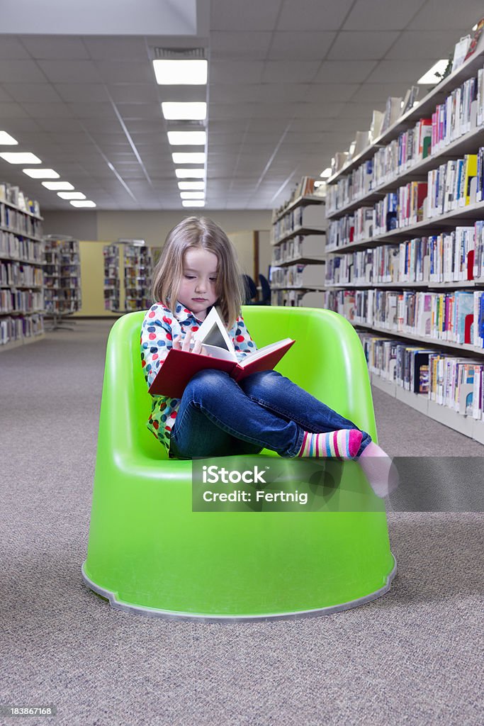 Menina lendo um livro na biblioteca - Foto de stock de Aluno de Jardim de Infância royalty-free