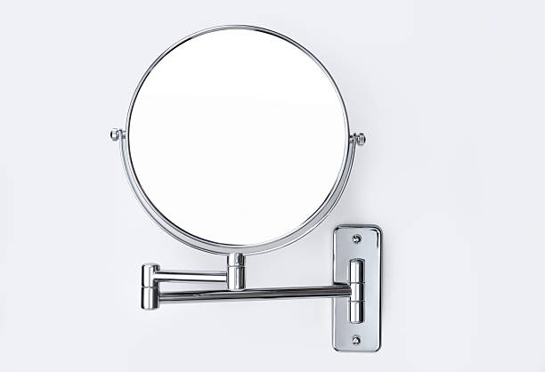 Round wall-mounted mirror "A round, wall-mounted mirror with chrome articulated arm on white background" vanity mirror stock pictures, royalty-free photos & images