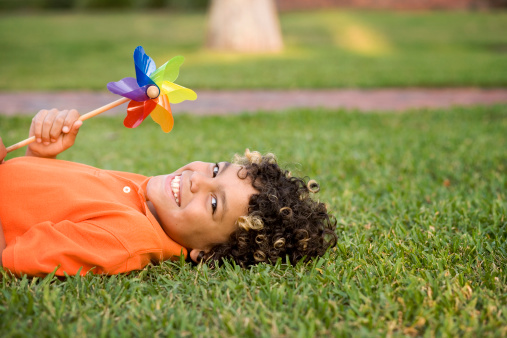Cute mixed race boy holding a colorful pinwheel in the grass.