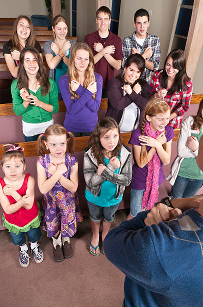 Group of Young People Signing a Song "A group of kids, from preschool to high school, signing a Sunday School song, showing the ASL sign for ""love""" american sign language photos stock pictures, royalty-free photos & images
