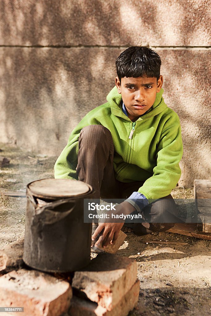 Indian boy preparing food on the street, Delhi. India "Poor Indian children preparing food on the street in Delhi.. Many Indian children suffer from poverty - more than 50% of India's total population  lives below the poverty line, and more than 40% of this population are children." Child Stock Photo