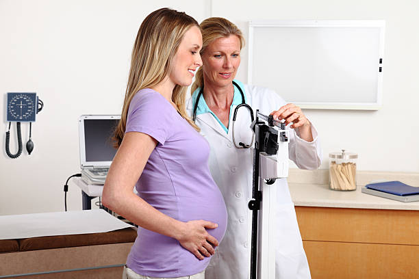Pregnancy Weight Check XXXL.  Pregnant woman's weight being checked by doctor. gchutka stock pictures, royalty-free photos & images