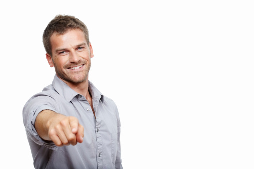 Portrait of casual man smiling and pointing at you on white background - with copy space