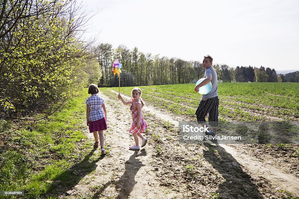 father and daughters outdoors father and 2 daughters on a field, father holding globe ball, youngest daughter a windmill 4-5 Years Stock Photo