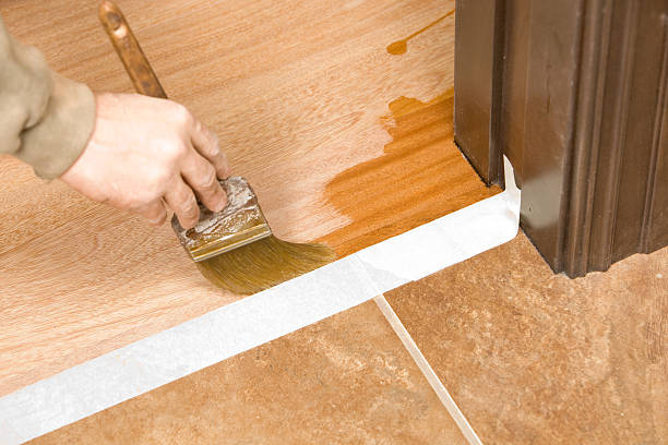 Painter Brushing Clear Polyurethane on Hardwood Floor stock photo