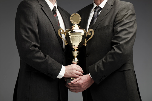 two businessman sharing a trophy