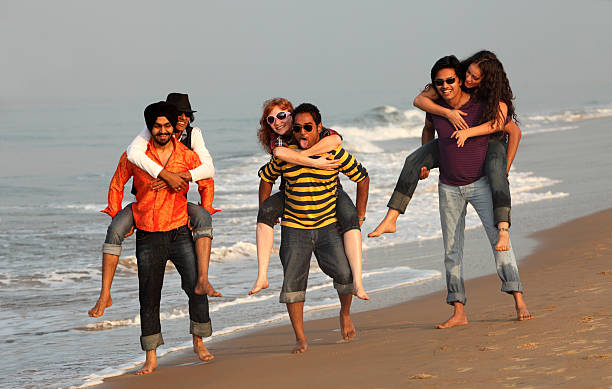 Good time on the beach in India Young people having fun on the beach in Goa, running toward the camera in shallow water on the sand. This is a diverse group of people, some Indians, some Caucasian, some mixed race. beach goa party stock pictures, royalty-free photos & images