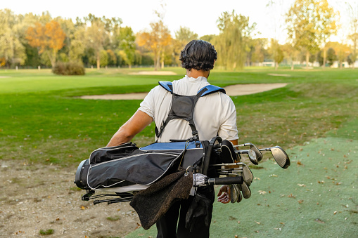 The golfer enters the golf course with a bag on his back - Stock Photo