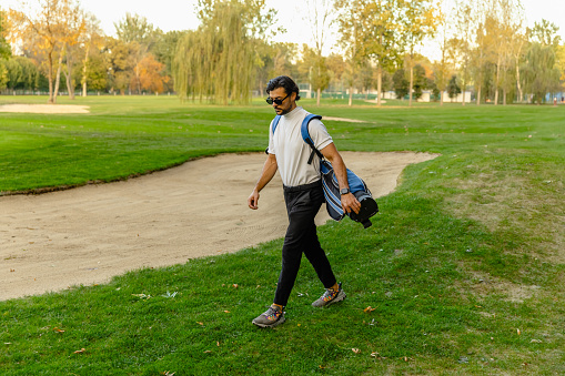 The golfer enters the golf course with a bag on his back - Stock Photo