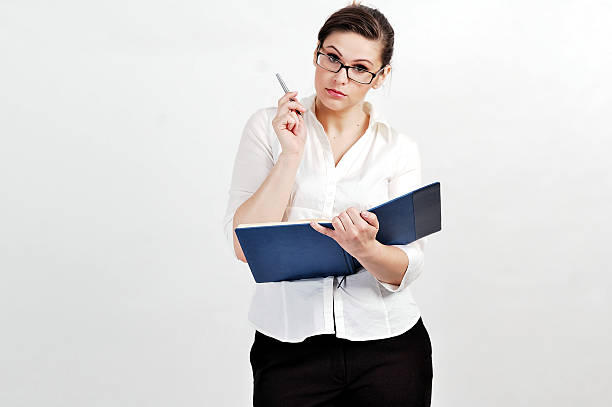 Portrait of  a young businesswoman Portrait of young businesswoman wearing glasses; standind and holding calendar and inkpen. inkpen stock pictures, royalty-free photos & images