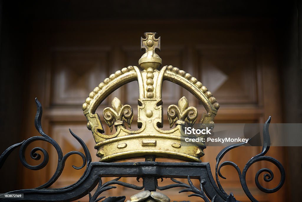 Decorative Gold Crown on Wrought Iron Gate A decorative, gilded crown on a wrought iron fence outside London's National Portrait Gallery with a wood panel door in the background. Royalty Stock Photo