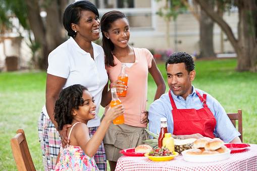 African American family having cookout in back yard.  (Girl seated is out of focus)