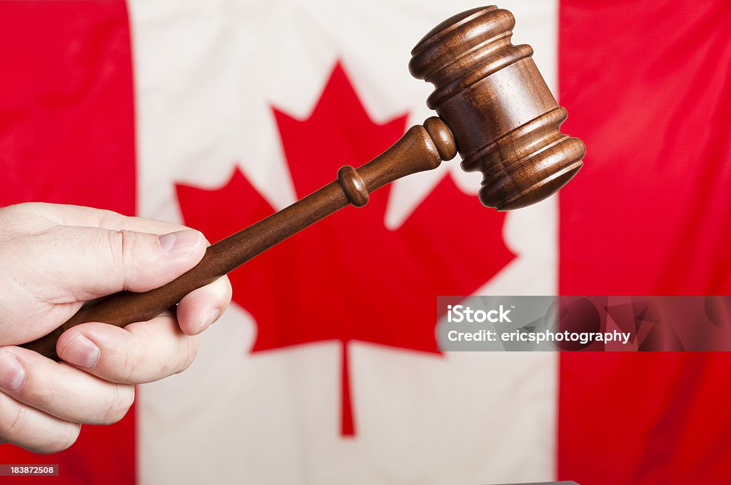 Canadian justice Male hand holding gavel. The Maple Leaf in the background. Selective focus. Agreement Stock Photo