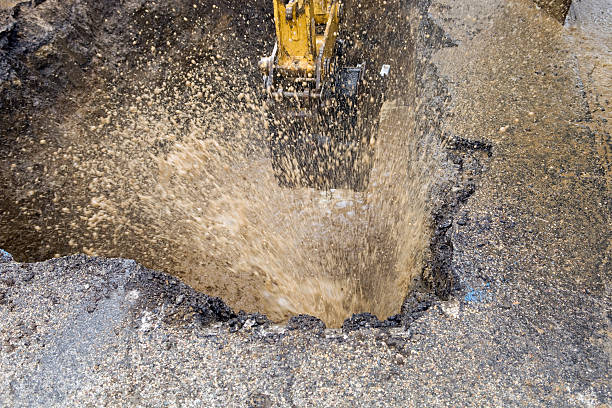 Excavator Operator Digging A Hole On Road To Pipeline Replacement On The City Street