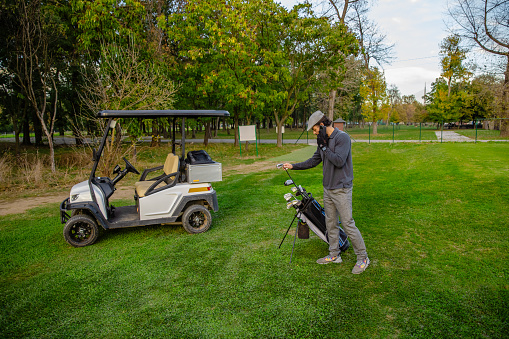 Golfer on the golf course is talking on the phone - Stock Photo