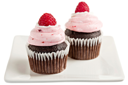 Two chocolate raspberry cupcakes  on a square white plate.