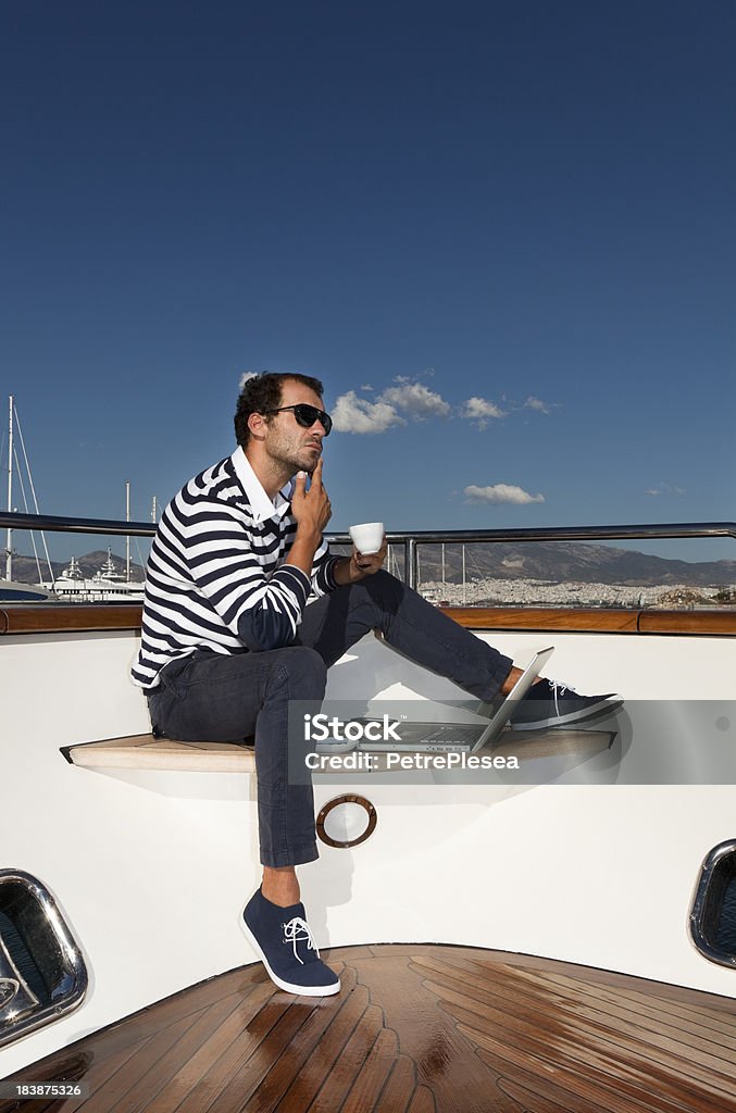 Uomo d'affari rilassante e bere caffè a bordo dello yacht. - Foto stock royalty-free di Abbigliamento casual