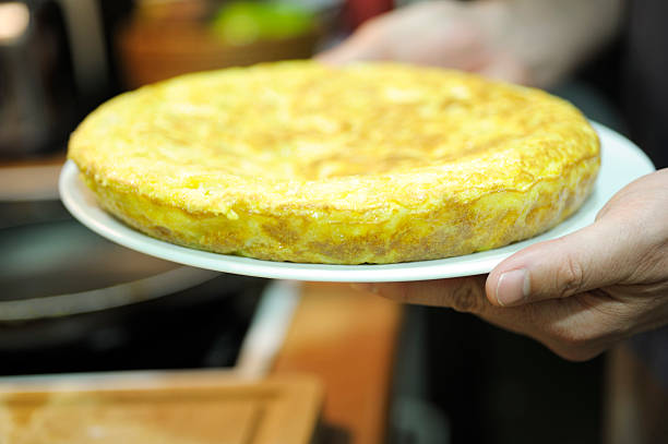 Close-up of a homemade Spanish tortilla de patatas (potato omelette) served on a plate with multiple toothpicks inserted for easy sharing. A classic tapa dish commonly found in Spanish cuisine, perfect for parties and gatherings.