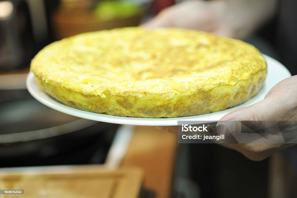 Spanish omelette straight out of the pan "A traditional Spanish omelette or tortilla, made with potatoes stewed till soft in olive oil, added to beaten egg and gently fried to make a deep omelette. Peppers and ham are optional extra ingredients. Although this can be a hot dish, slices of cold tortilla are also eaten in Spain as snacks and for breakfast." Omelet Stock Photo