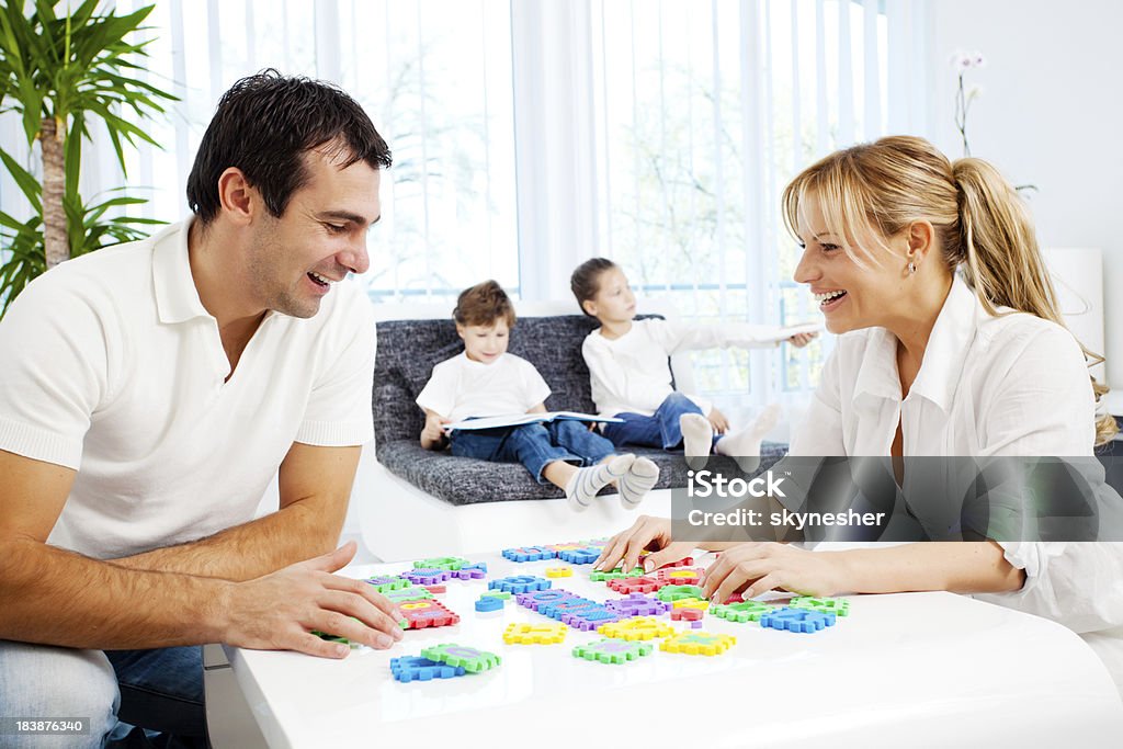 Pais jogando jogo de palavras enquanto as crianças são sentada no sofá. - Foto de stock de Adulto royalty-free