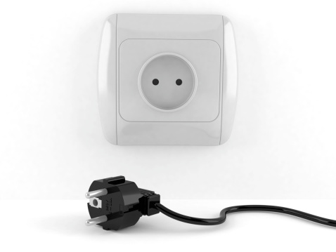 electrical socket and plug in it, against the background of a gray wall
