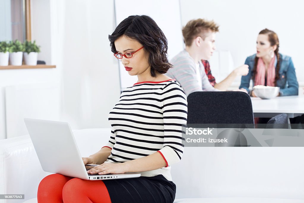 Donna asiatica utilizzando computer portatile - Foto stock royalty-free di Abbigliamento casual
