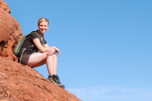 A happy female hiker at the top of a rock formation with a confident smile.