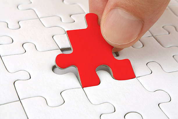 istock Red jigsaw puzzle piece being placed in all-white puzzle 183878873