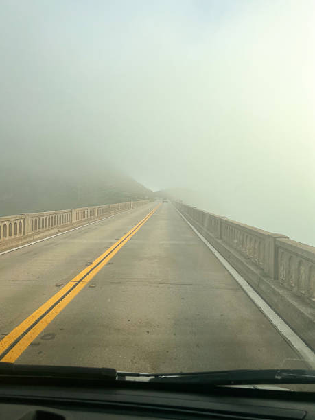 nebel umhüllt die bixby-brücke in der nähe der felsigen küste von big sur - fog bridge california balance stock-fotos und bilder