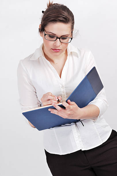 Portrait of  a young businesswoman Portrait of young businesswoman making notes; standind and holding calendar and inkpen. inkpen stock pictures, royalty-free photos & images