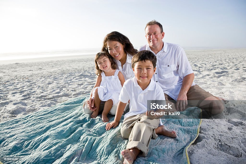 interracial sorridente famiglia seduta sulla spiaggia - Foto stock royalty-free di 2-3 anni