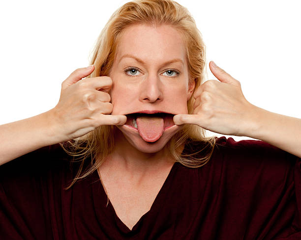 weibliche porträt - making a face mischief sticking out tongue isolated on red stock-fotos und bilder