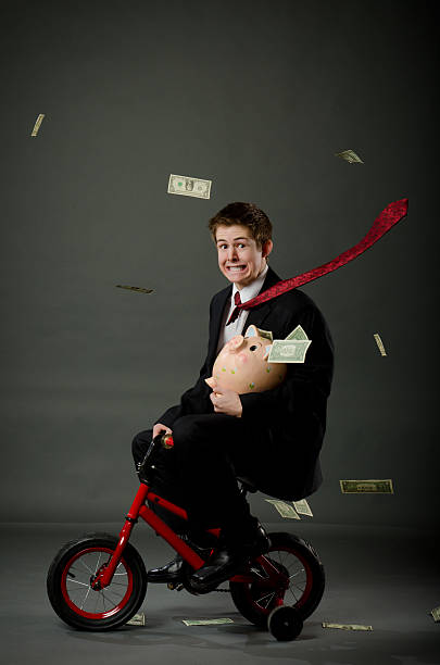 jungen wohlhabenden banker riding kleine fahrrad - stützrad stock-fotos und bilder