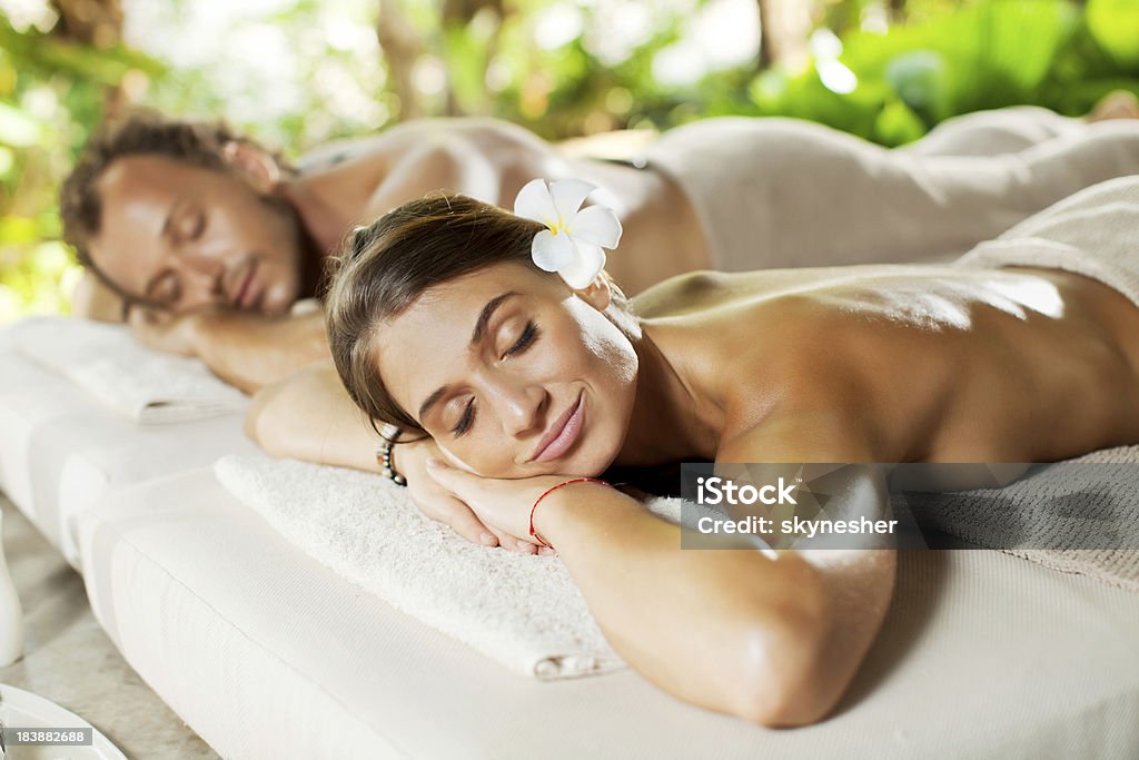 Relajación en pareja con ojos cerrados que reciben terapia de piedras calientes. - Foto de stock de Acostado libre de derechos