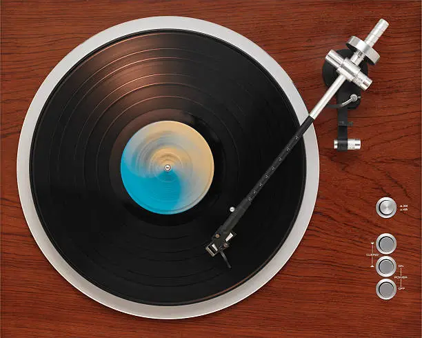 An old turntable from the '70s playing a record album. Direct overhead view.