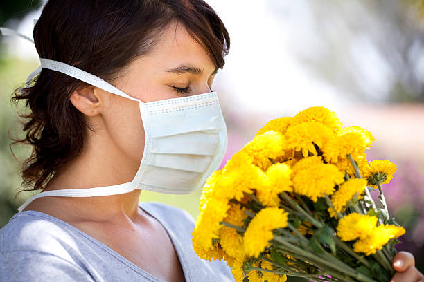 istock Allergic young woman smelling flowers 183883410
