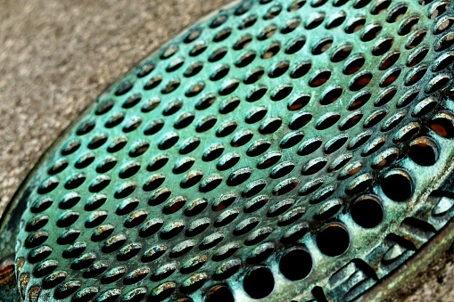 A lovely green patina on an old vent or drain cap.