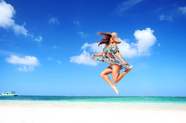 Carefree young woman is jumping into the sky stock photo