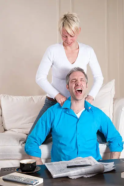 Photo of Woman vigorously massaging man shoulders.