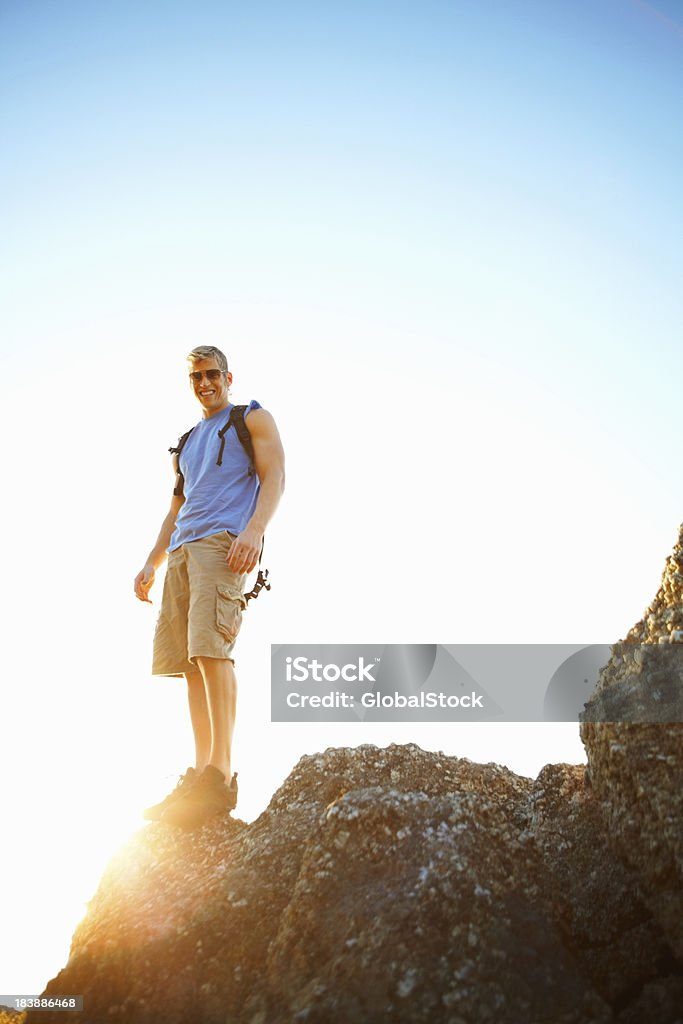 Giovane uomo in piedi al bordo di una rock - Foto stock royalty-free di Adulto