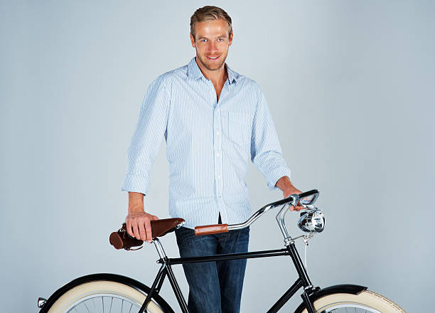 Handsome business man standing next to retro bicycle on blue background