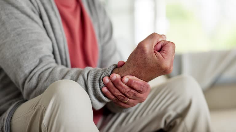 Hands, wrist pain or fibromyalgia with a senior person closeup in the living room of a retirement home. Medical, massage or osteoporosis and an elderly adult with a joint injury or arthritis disease