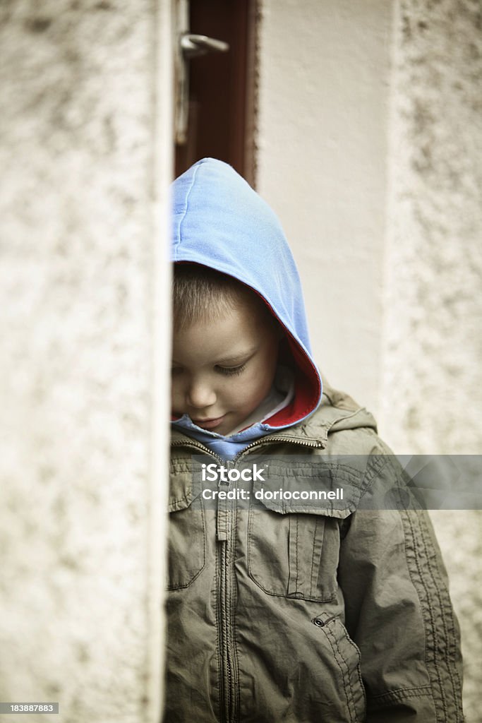 at the back door little boy standing at the back door, looking down Child Stock Photo