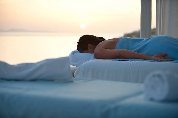 Massage table with massage oils and towels by pool side early in the morning