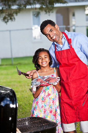 African American father, 40s, and daughter, 8 years, with barbecue grill