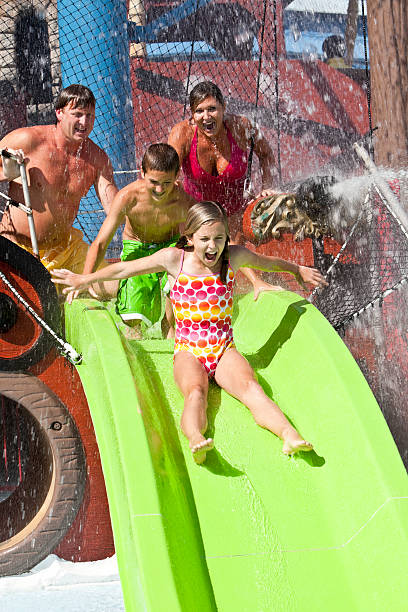 istock Family with girl going down slide at water park 183889113